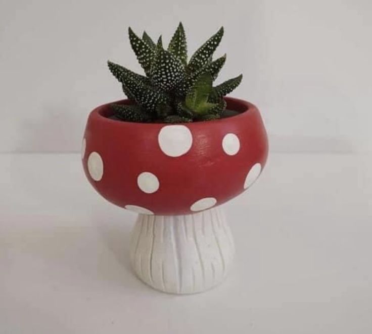 a red and white mushroom planter with polka dot dots on it's base