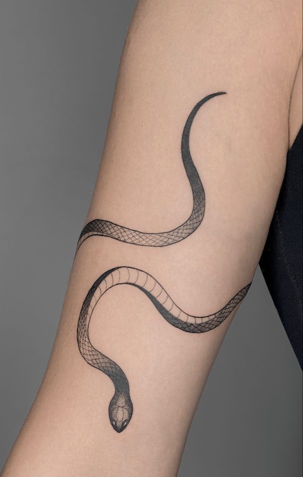 a woman's arm with a black snake tattoo on the left side of her body