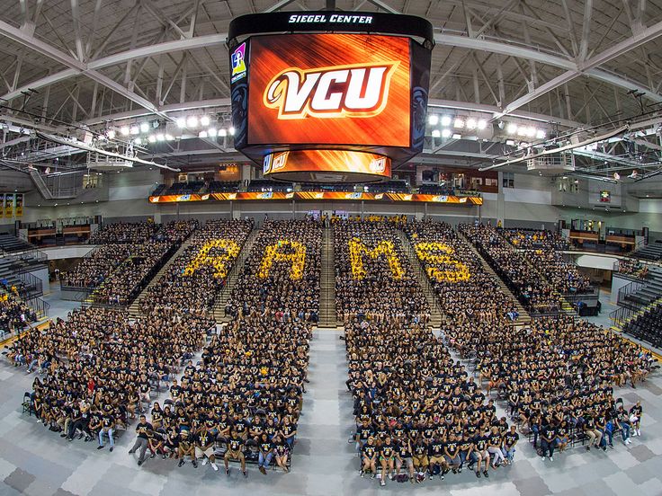 a large group of people standing in front of a big screen at a sporting event