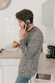 a man talking on his cell phone in the kitchen