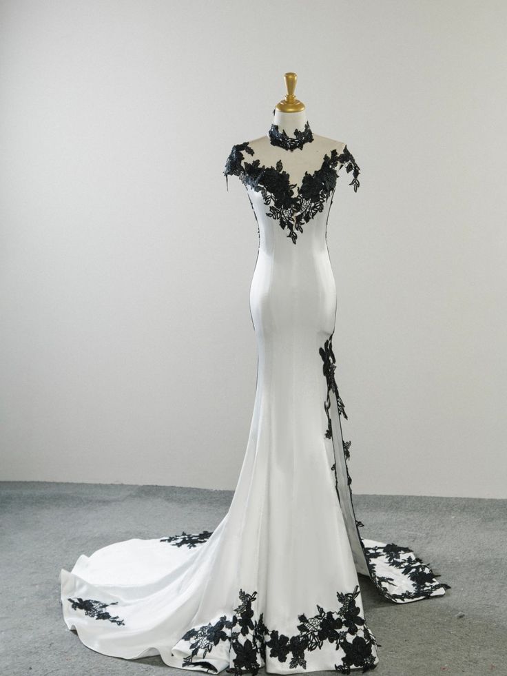 a white and black wedding dress on display in a room with gray flooring,