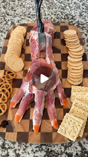 a wooden cutting board topped with meat and crackers