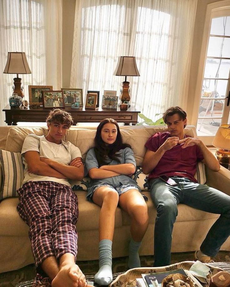 three people sitting on a couch in a living room