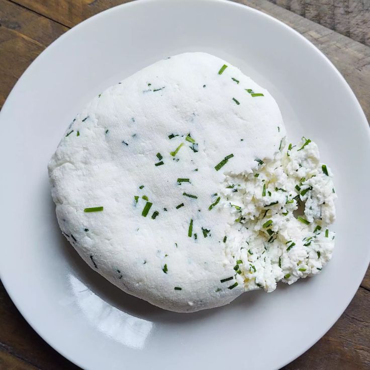 a white plate topped with two pieces of food on top of a wooden table next to a knife and fork