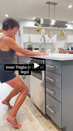 a woman standing in front of an oven with her leg up on the counter top