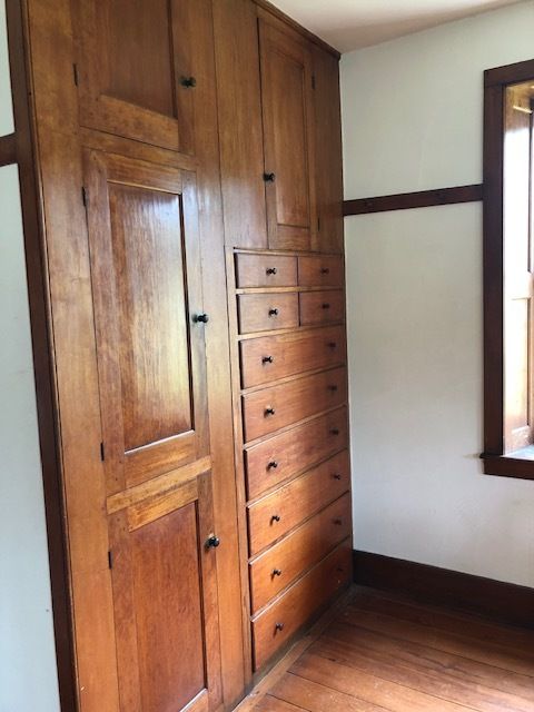 an empty room with wooden cabinets and drawers on the wall, in front of a window