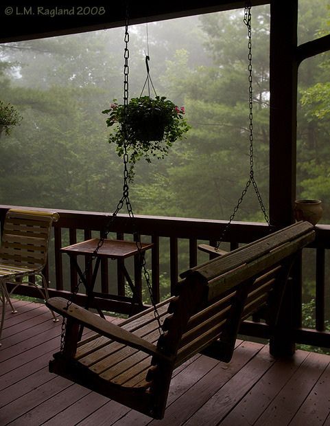 a wooden porch with a swing chair and potted plant hanging from it's side