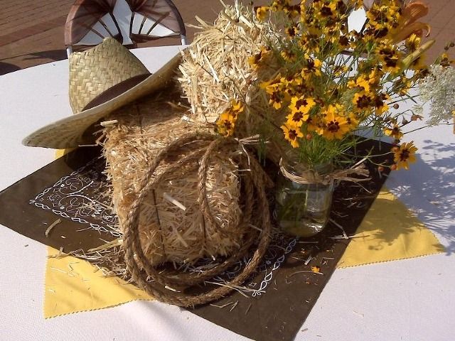 a table topped with a vase filled with flowers next to a straw hat and rope