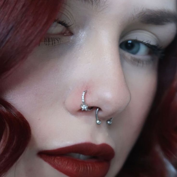 a woman with red hair and piercings on her nose