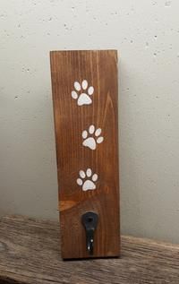 a bottle opener with paw prints on it sitting on top of a wooden shelf next to a wall