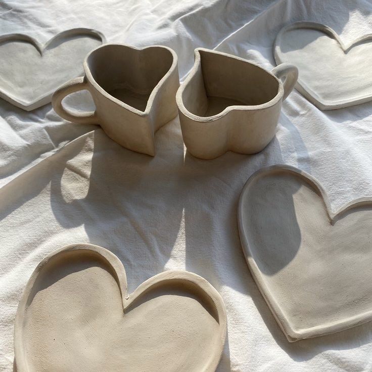 three heart shaped dishes sitting on top of a white cloth covered table next to each other