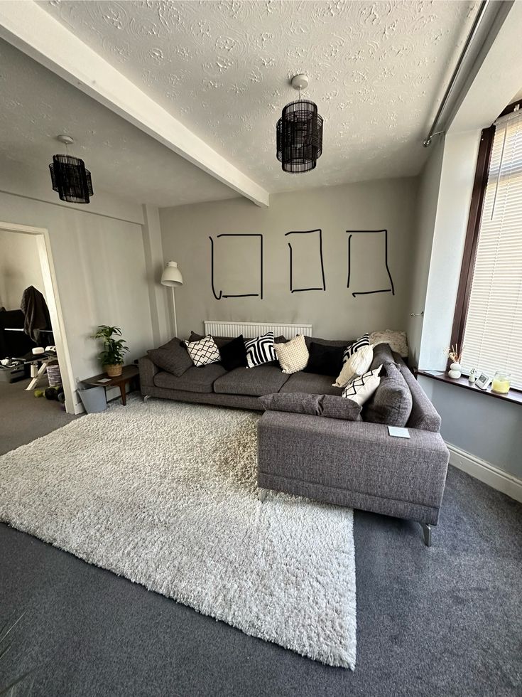 a living room filled with furniture and a large rug on top of a carpeted floor