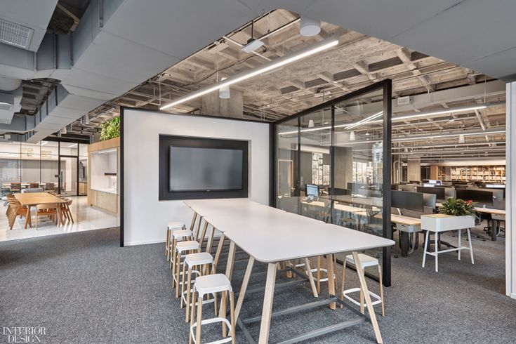 an office with tables, chairs and a flat screen tv in the middle of it