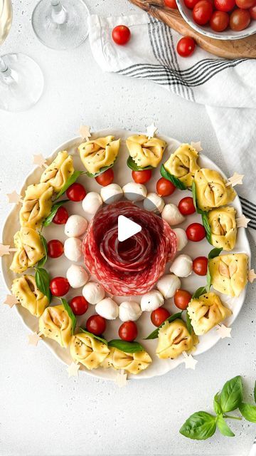 a white plate topped with pasta and veggies on top of a table next to wine glasses