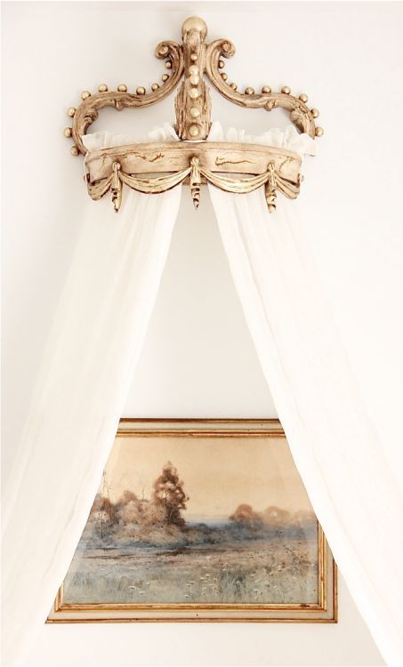 a painting hanging on the wall above a bed with white drapes over it's head