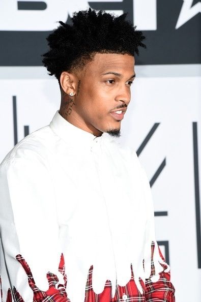 a young man with black hair wearing a white shirt and red plaid pants at an event