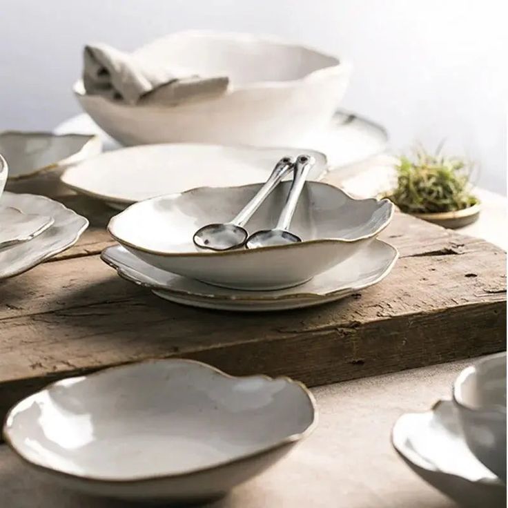 a table topped with lots of white plates and bowls