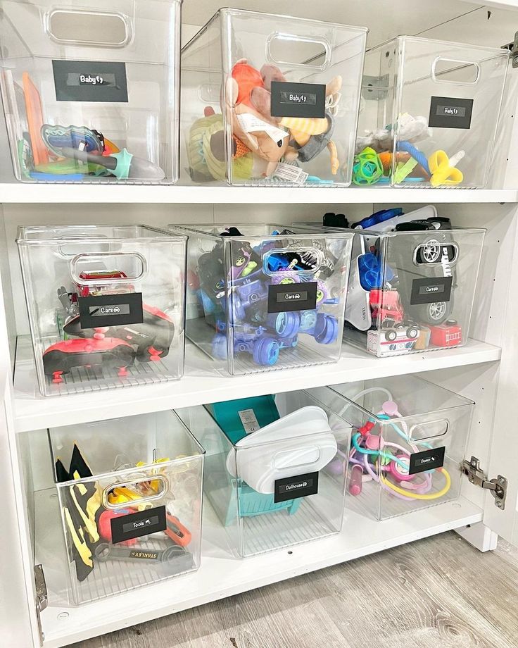 clear bins filled with toys and other items on top of a white shelving unit