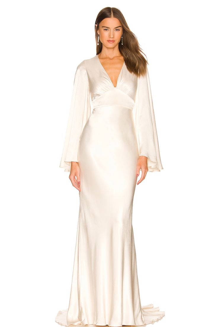 a woman wearing a white gown with long sleeves