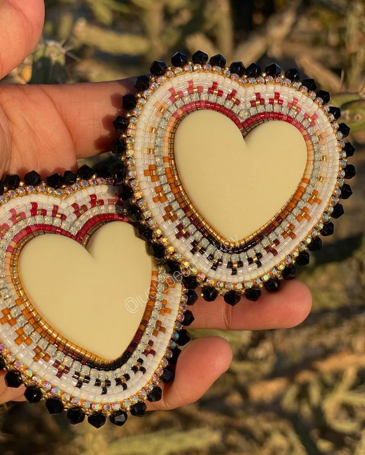 two heart shaped brooches are being held in the palm of someone's hand