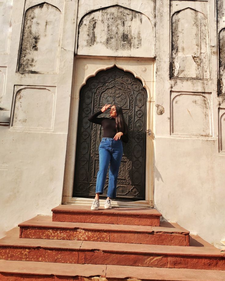 a woman standing on some steps in front of a building with an ornate door and window