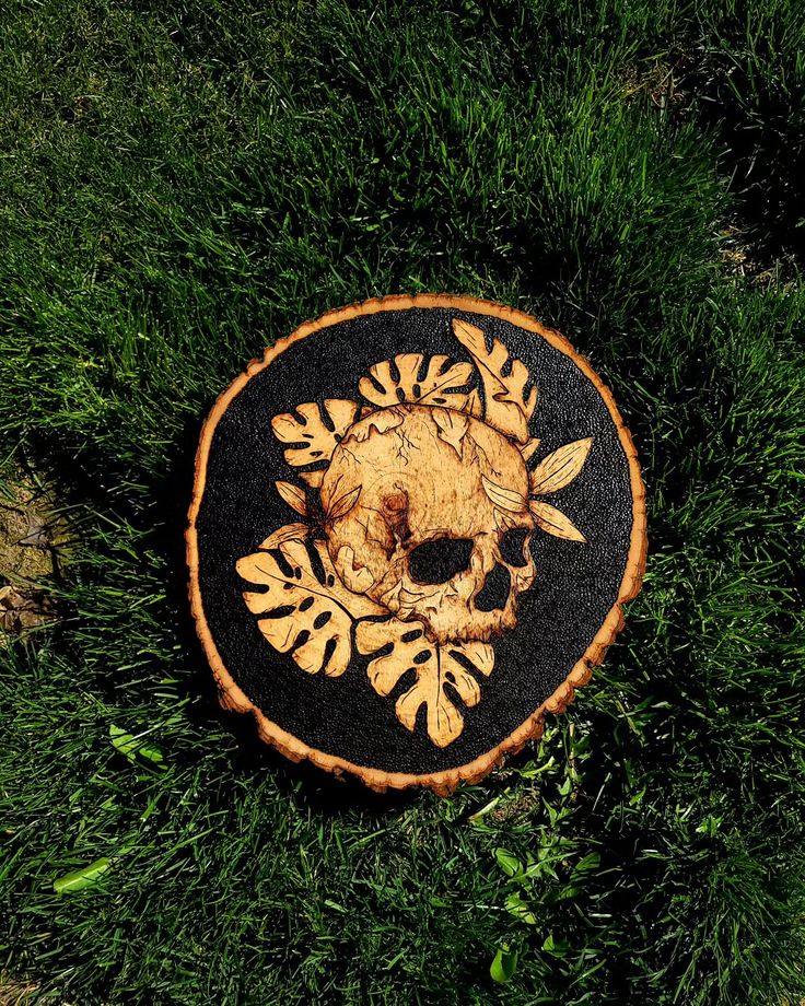 a black and white patch with a skull on it in the grass next to some leaves