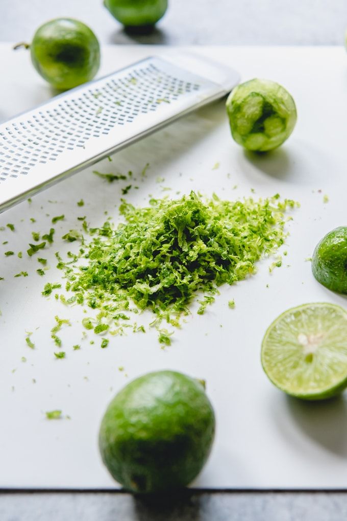 limes are cut up on a cutting board with a grater