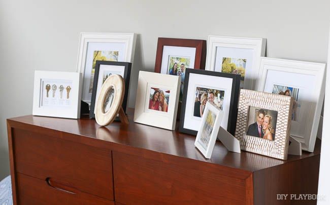 there are many frames on the dresser with pictures