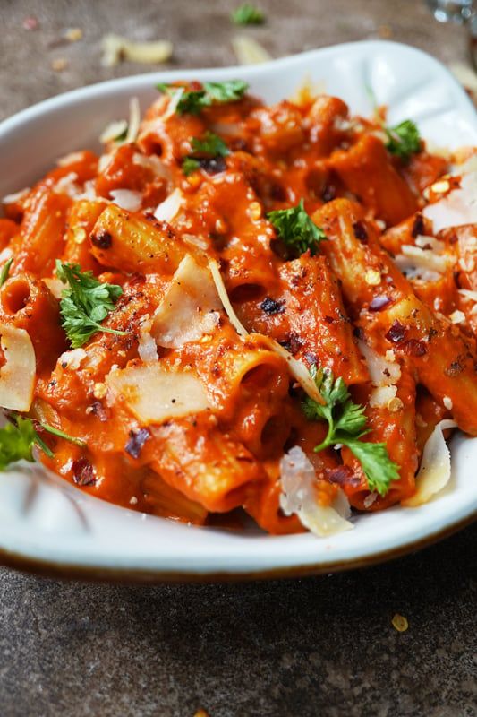 a white bowl filled with pasta covered in sauce and parmesan cheese