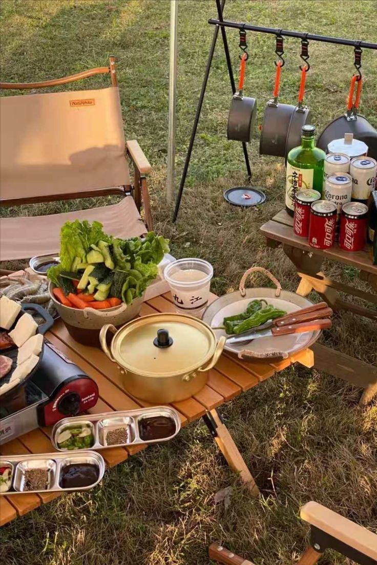 a picnic table with food and drinks on it in the middle of a grassy field