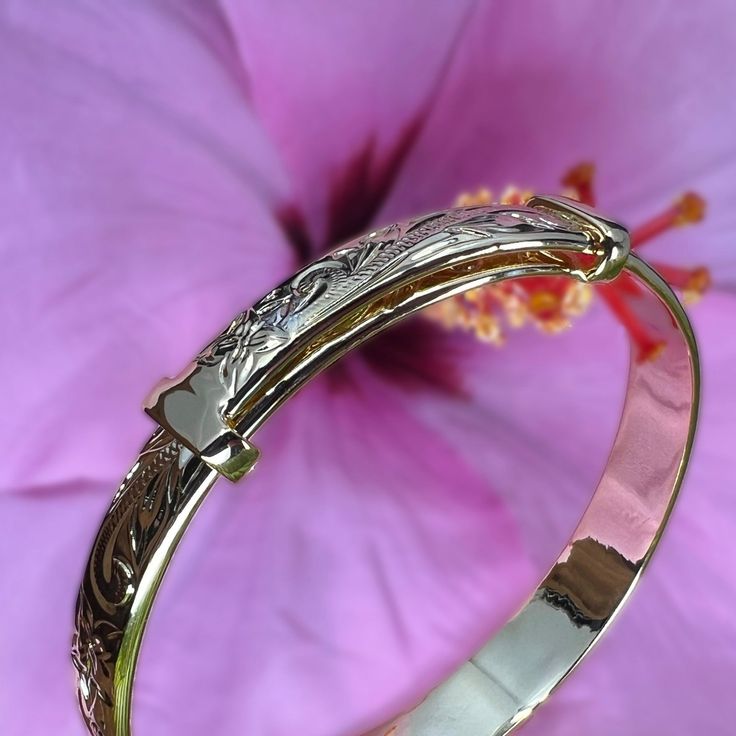 Everyone was asking for a Hawaiian Scroll Bangle that didn’t require a size, so we designed a new one just for you! This beautiful adjustable bangle is Gold Plated over Brass so it’s super affordable! Exquisite Hawaiian scrollwork adorns the whole bracelet as it adjusts from size 7.5 all the way up to size 9. The comfortable design tapers from 10mm to 5mm and is great for all ages! 14K gold plated over Brass Adjusts from size 7.5 to size 9 Tapered Design from 10mm to 5mm wide Hand engraved Hawai Polished Bangle Bracelet For Promise Occasion, Adjustable Engraved Round Bangle, Adjustable Engraved Bangle Bracelet, Engraved Adjustable Bangle Name Bracelet, Adjustable Yellow Gold Bracelet With Intricate Design, Adjustable Bracelets With Intricate Design, Adjustable Round Engraved Bracelet, Adjustable Engraved Round Bracelet, Adjustable Engraved Bracelets