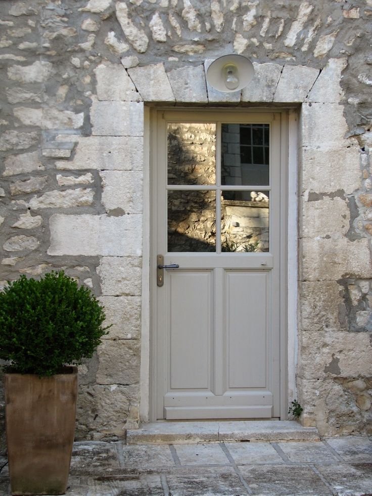 a potted plant sitting in front of a stone building with a white door and window