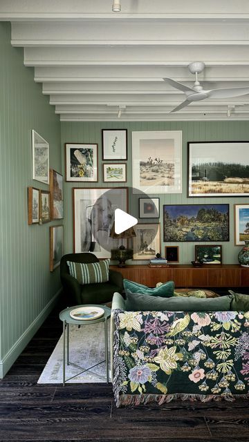 a living room with green walls and pictures on the wall above the couch, along with a coffee table