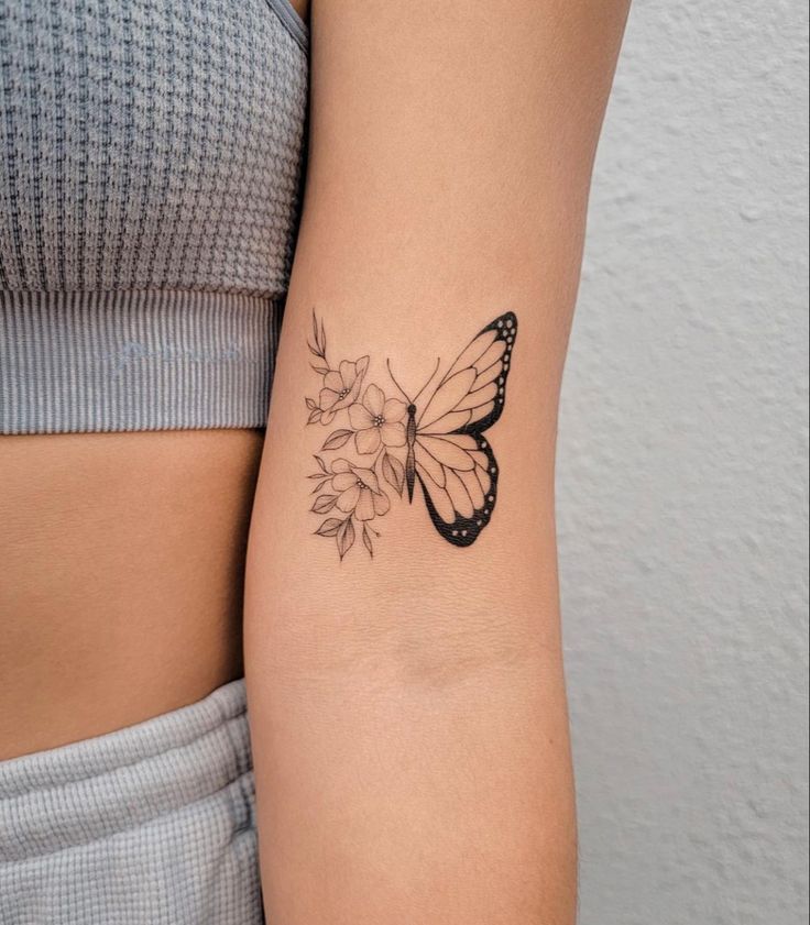 a woman's arm with a butterfly and flower tattoo on the left side of her arm