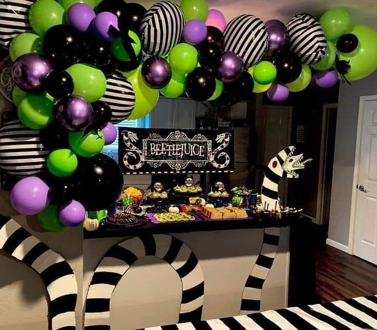 a party with black, white and green balloons in the shape of an arch over a buffet table