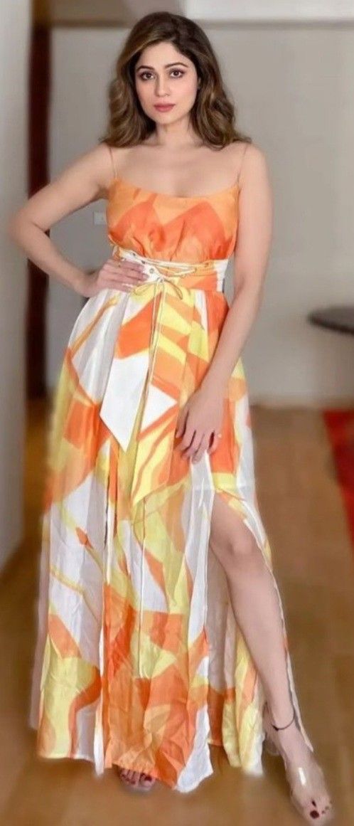 a woman in an orange and white dress posing for the camera