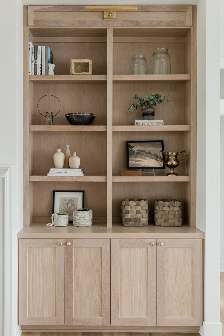 a wooden bookcase filled with lots of books and vases on top of it