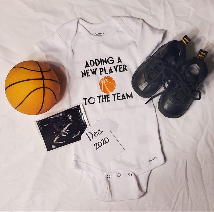 a baby's bodysuit and shoes are laying on a bed next to a basketball