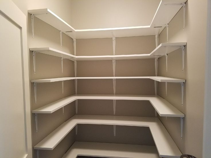 an empty walk in closet with white shelving