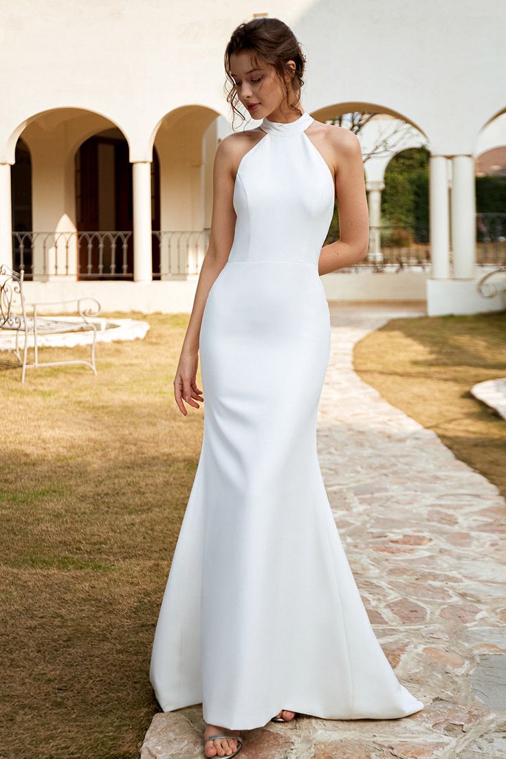 a woman in a white dress is standing outside