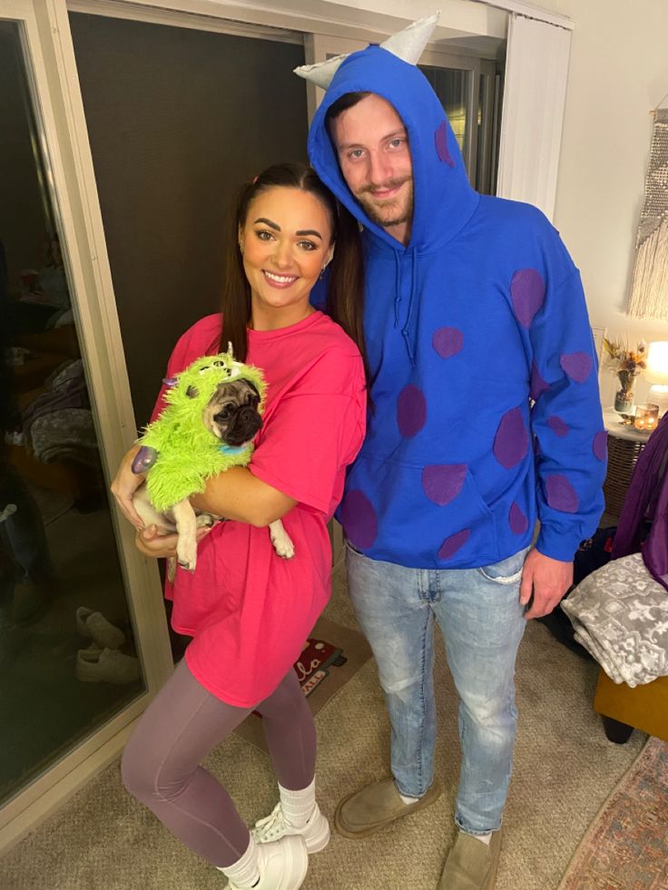 a man and woman in costumes standing next to each other holding a small pug