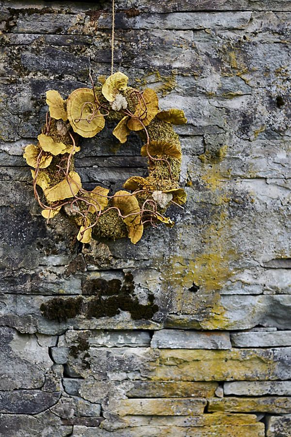 a wreath hanging on the side of a brick wall with moss growing out of it