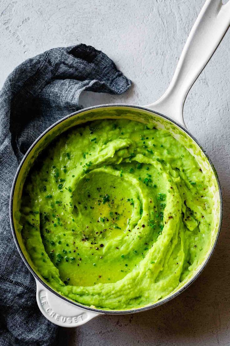 a pot filled with green guacamole on top of a gray countertop