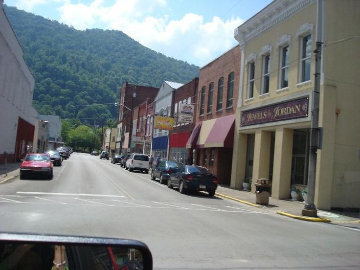 cars are driving down the street in front of shops and businesses on a sunny day