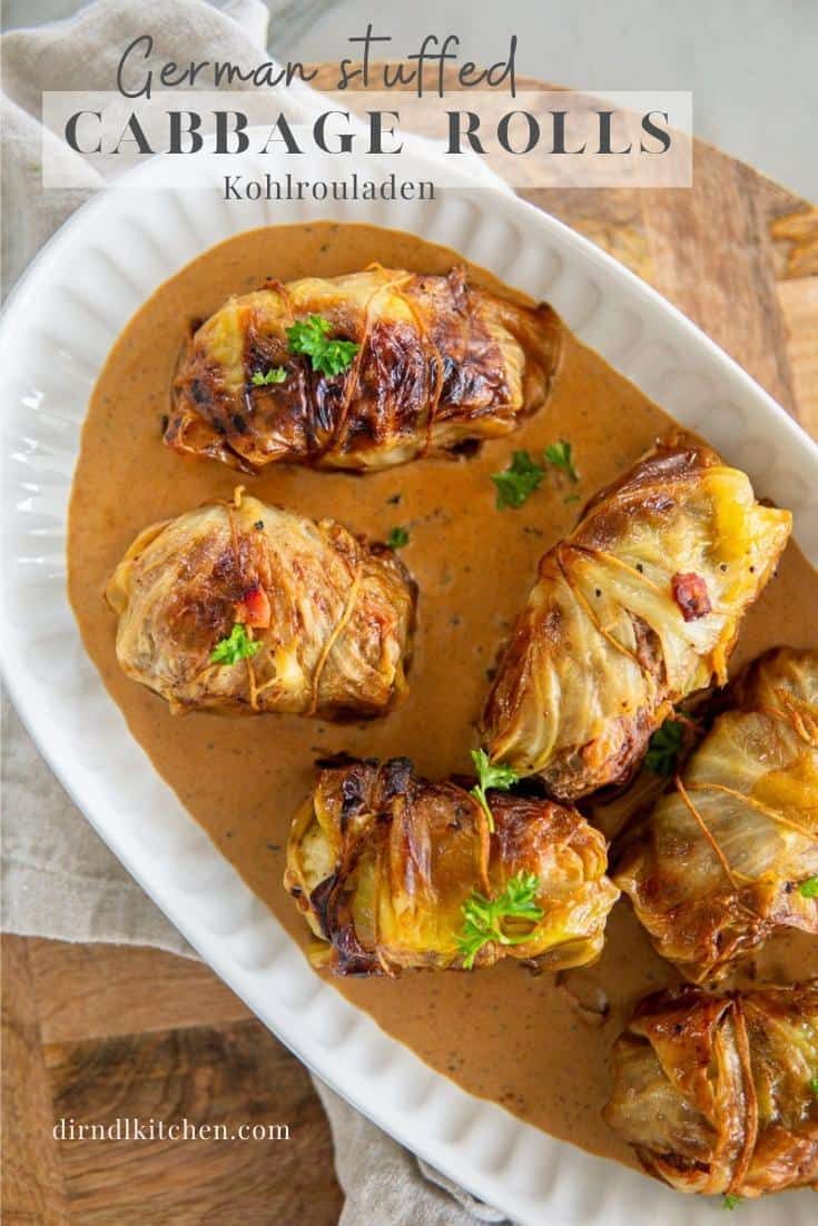 baked stuffed cabbage rolls with gravy in a white dish on a wooden table