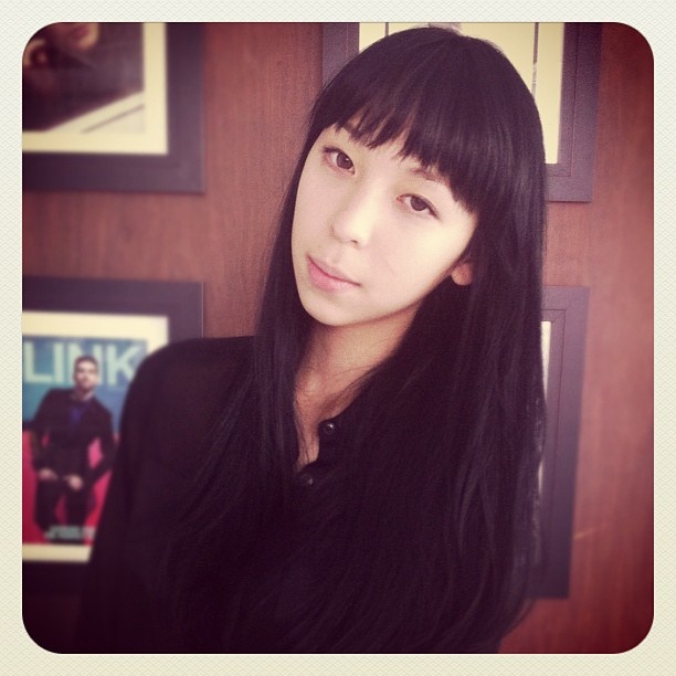 a woman with long black hair standing in front of a door