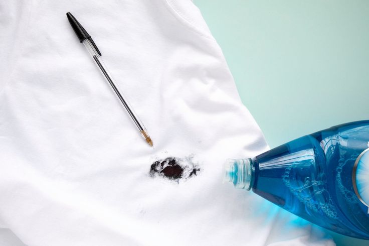 a blue bottle with some paint and a brush on it next to a white t - shirt