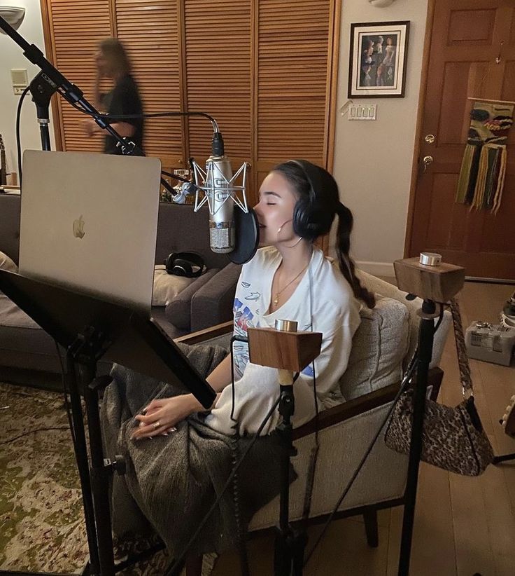 a woman sitting in a chair with a laptop on her lap and headphones over her ears