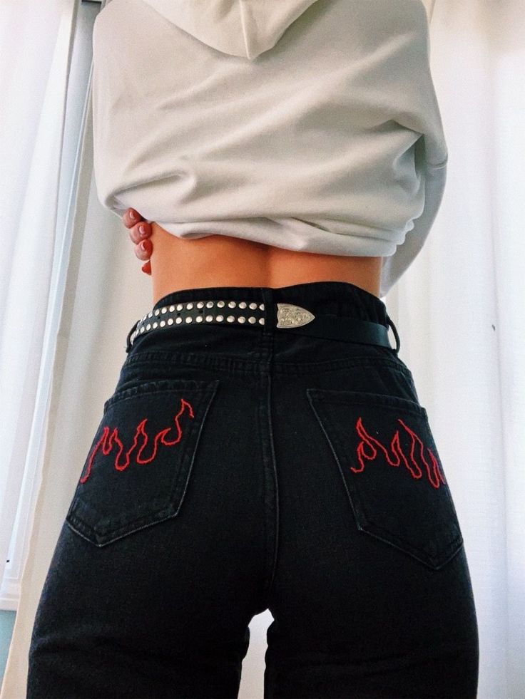 a woman wearing black jeans with red writing on the side and her bottom half showing