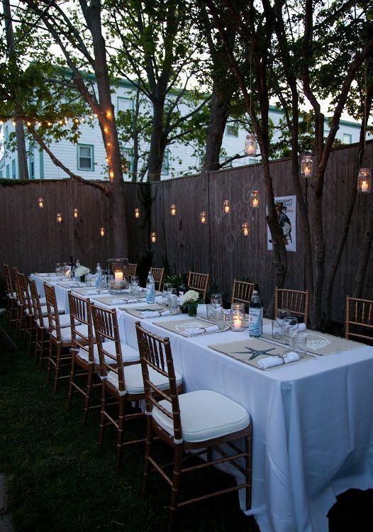 an outdoor dinner table set up with candles and place settings